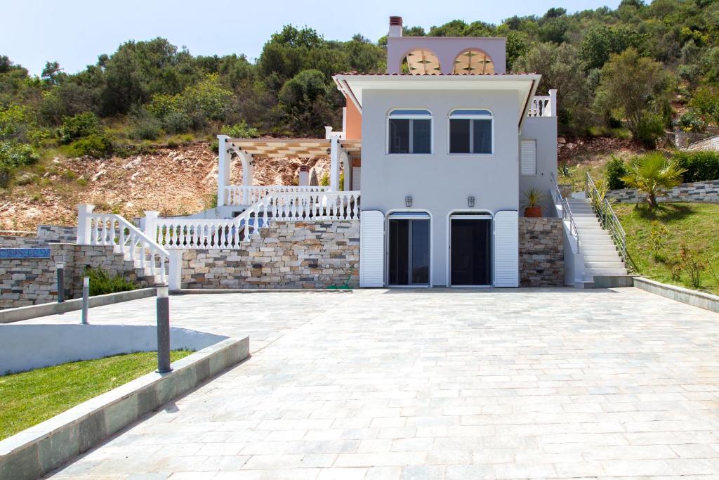 a white house with a white fence and a driveway at luxurylefkadavilla in Vasiliki