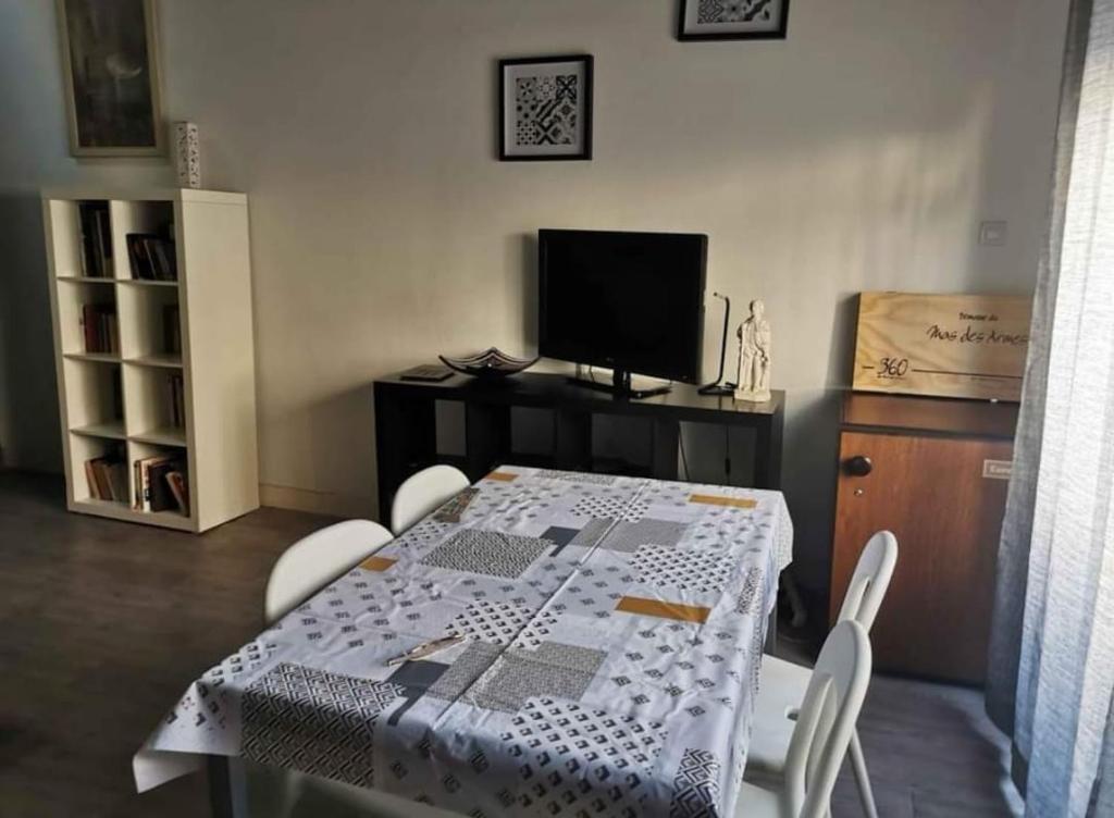 a dining room with a table and a tv at Particulier in Palavas-les-Flots