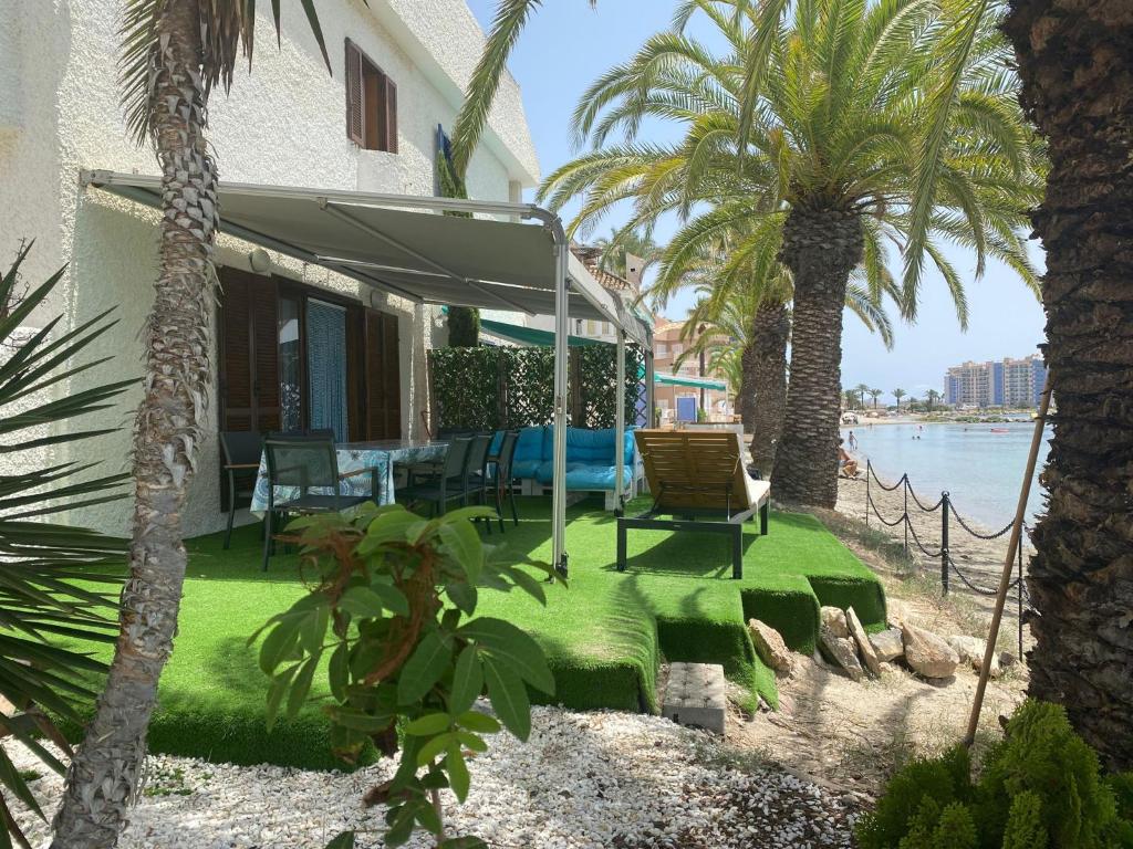 ein Haus mit Palmen, einem Tisch und Stühlen in der Unterkunft Chalet en mar menor in La Manga del Mar Menor