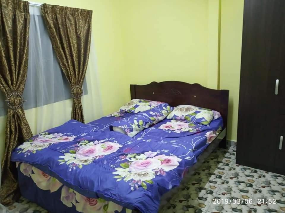 ein Bett mit einer lila Bettdecke und Kissen darauf in der Unterkunft La' Homestay in Kota Bharu