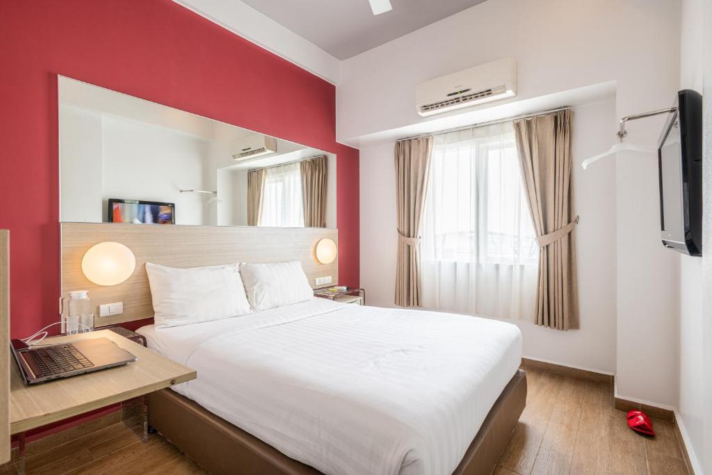 ein Hotelzimmer mit einem Bett und einem Schreibtisch mit einem Laptop in der Unterkunft Monoloog Hotel Pasar Baru in Jakarta