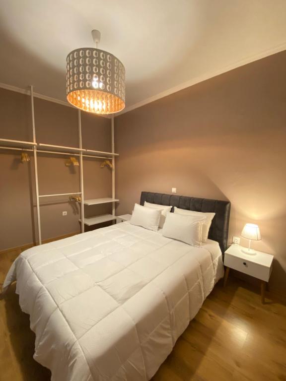 - une chambre avec un grand lit blanc et un lustre dans l'établissement Makao Apartment corfu, à Corfou