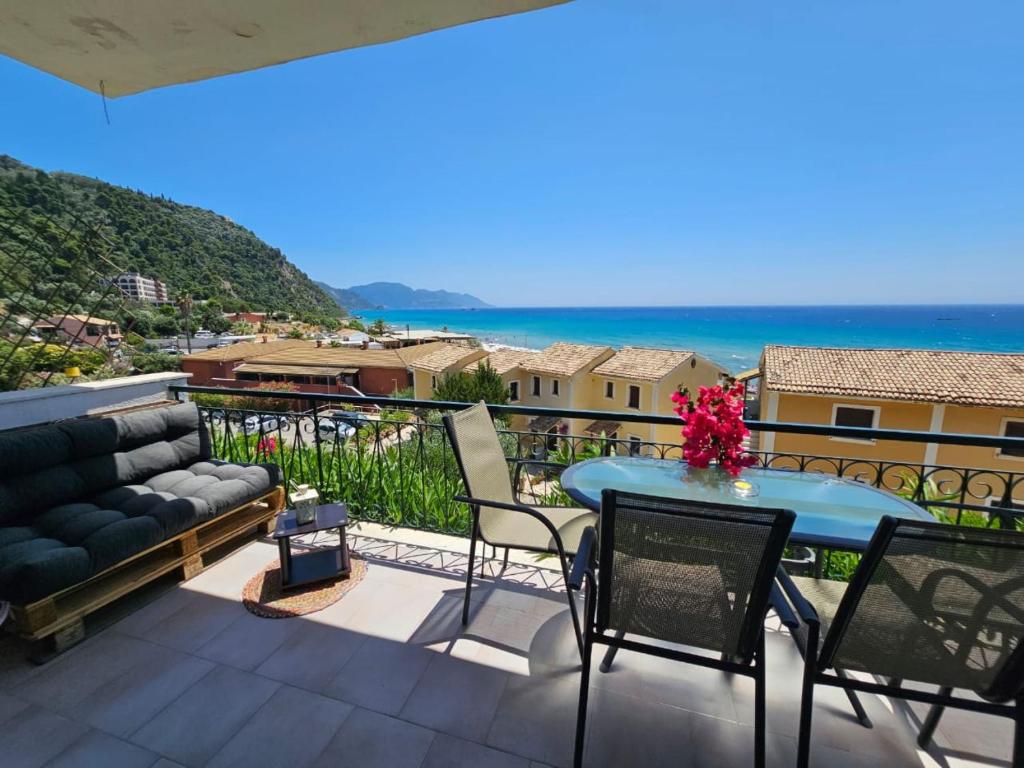a balcony with a couch and a table and the ocean at Corfu Glyfada Menigos Resort 149 in Glyfada