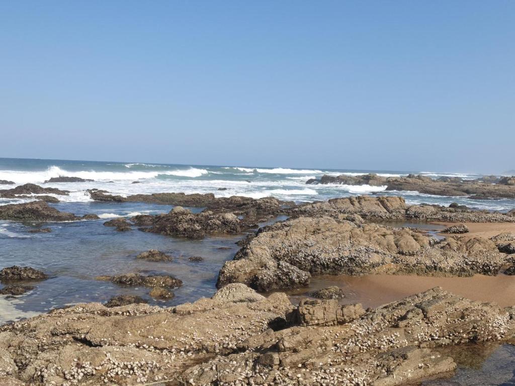 uma praia com pedras e o oceano com ondas em 3 Umzimkulu em Melville