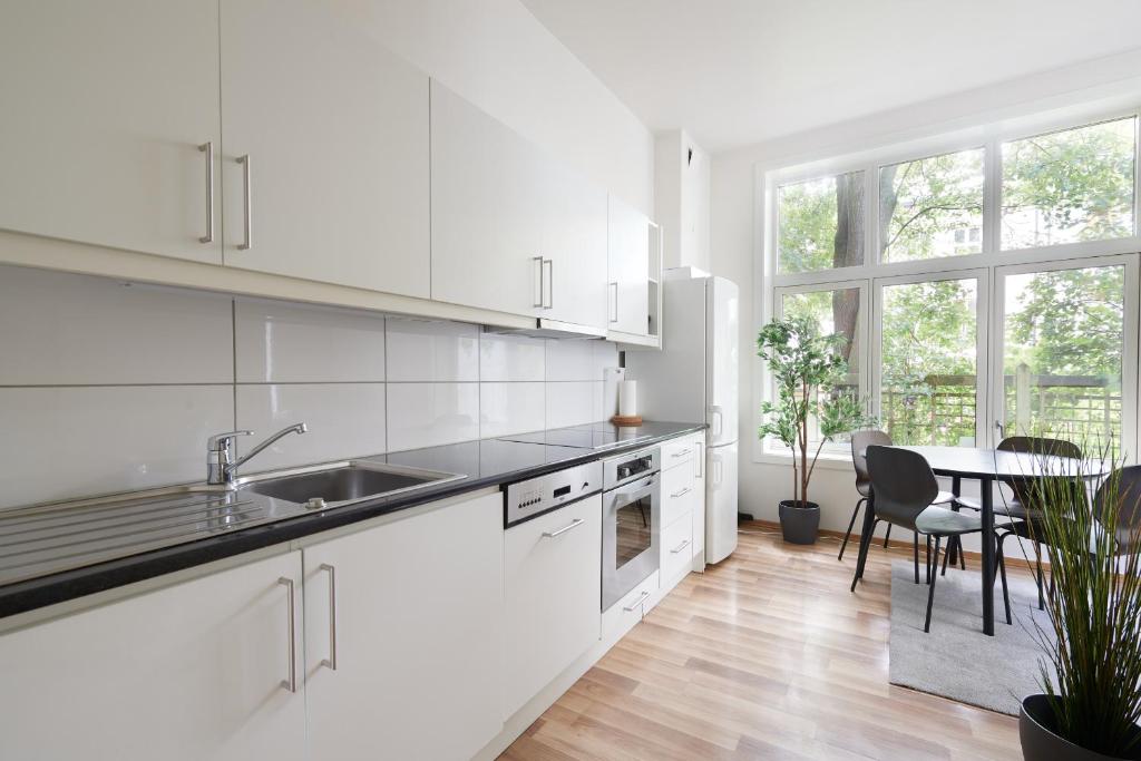 a white kitchen with a sink and a table at Grünerløkka shared Apartment Rooms in Oslo
