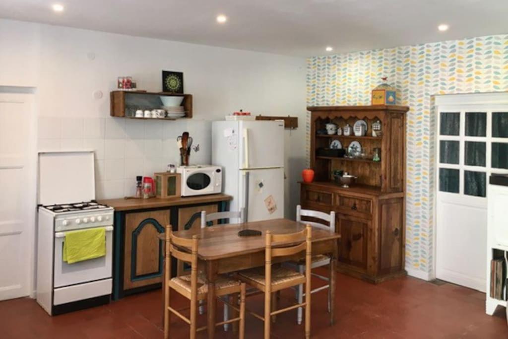 a kitchen with a table and a white refrigerator at Maison face à l&#39;étang in Précy