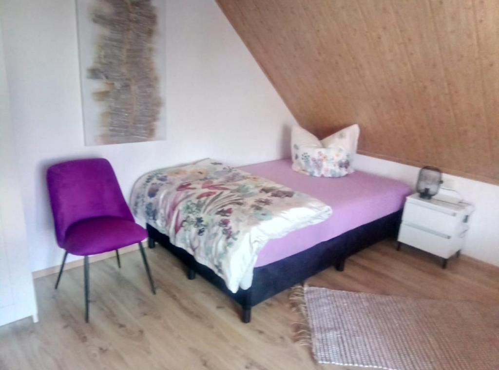 una camera con letto viola e sedia viola di Stadler Ferienwohnung a Neudörfles