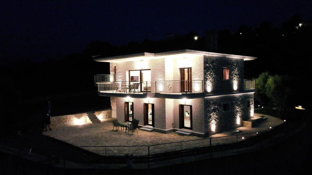 Cette grande maison blanche dispose d'un balcon la nuit. dans l'établissement Villa Oliveto con vista, à Leucade