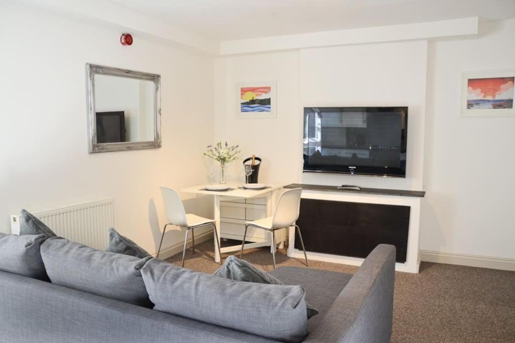 a living room with a couch and a tv and a table at Modern 1 bedroom apartment close to Penzance town centre. in Penzance