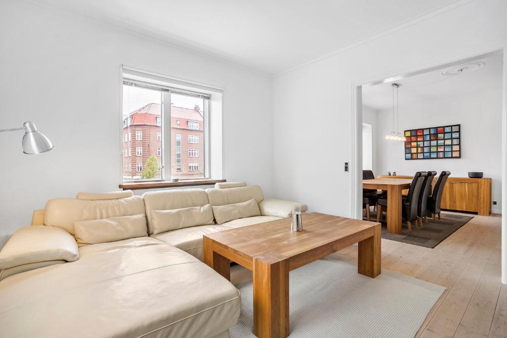 Cozy 2-Bed Apartment in Aalborg في ألبورغ: غرفة معيشة مع أريكة وطاولة