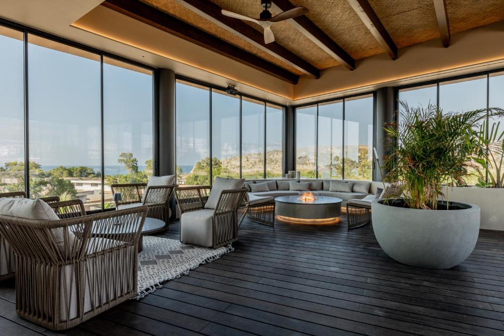 a living room with couches and chairs and windows at Pnoe Breathing Life - Adults Only in Karteros