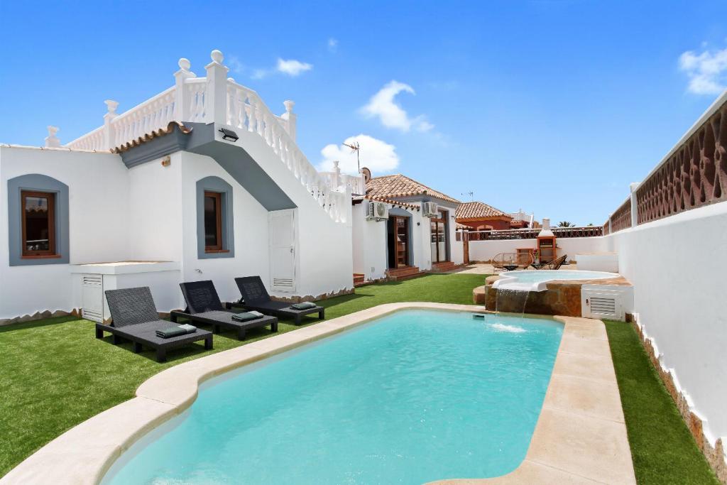 a backyard with a swimming pool and a house at Villa Thomas in Corralejo