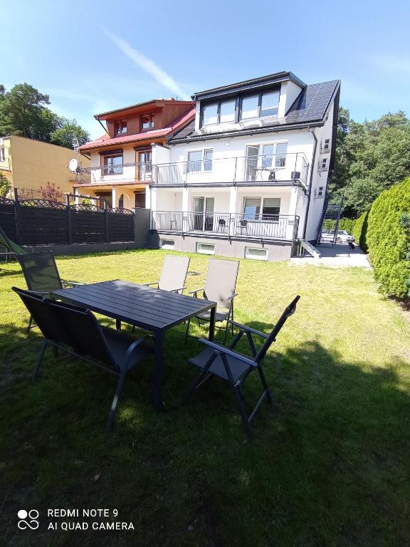 a picnic table and chairs in front of a house at Velobaltica apartmenty in Wisełka