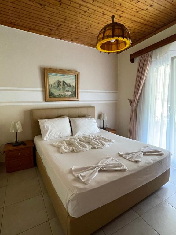 a bedroom with a large white bed with a chandelier at Avdikos House in Parga
