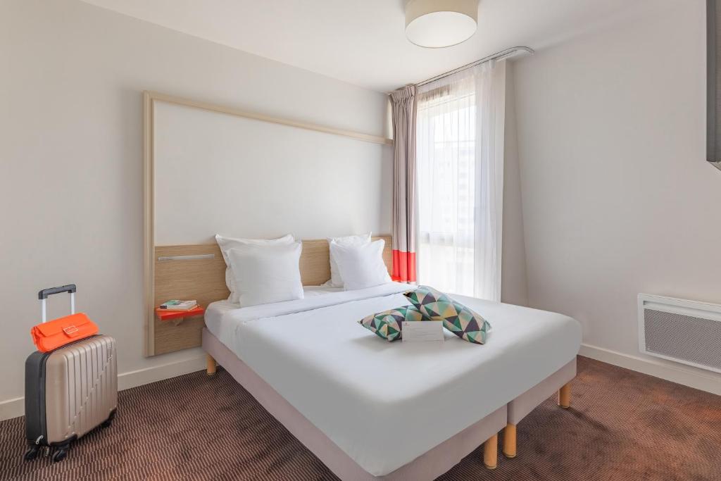Un dormitorio con una gran cama blanca y una ventana. en Appart'City Confort Bordeaux Chartrons, en Burdeos