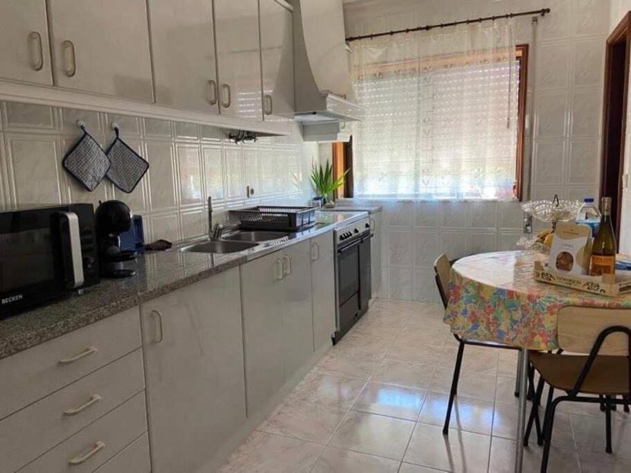 une cuisine avec des placards blancs, une table et un comptoir dans l'établissement Lovely 2 bedroom apartment 100m from the beach, à Vila do Conde