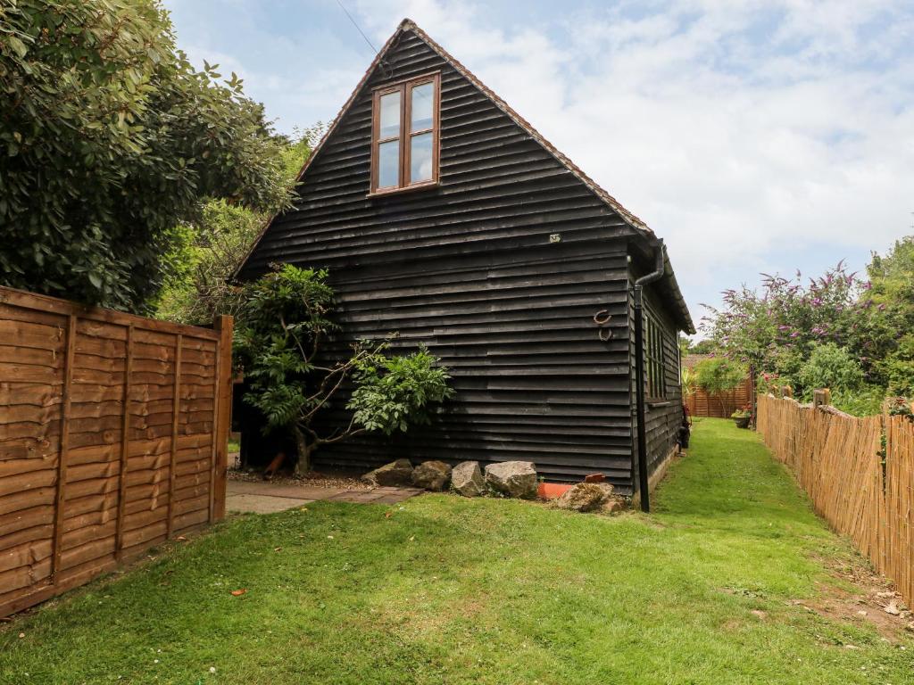 a black house with a fence in a yard at The Stables Barn in Arundel