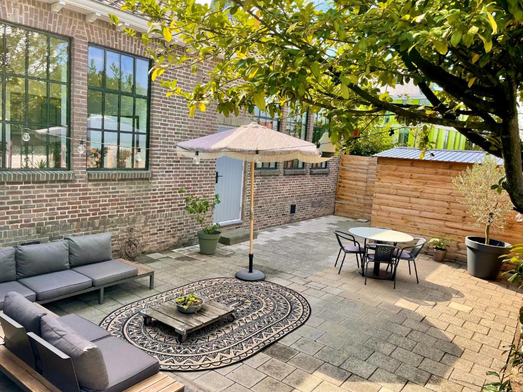 een patio met een bank, een parasol en een tafel bij Appartement de Oude School in Heerlen