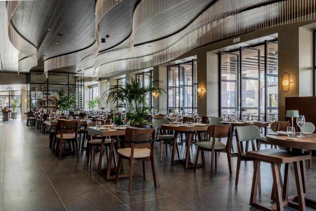 a restaurant with wooden tables and chairs and windows at Pnoe Breathing Life - Adults Only in Karteros
