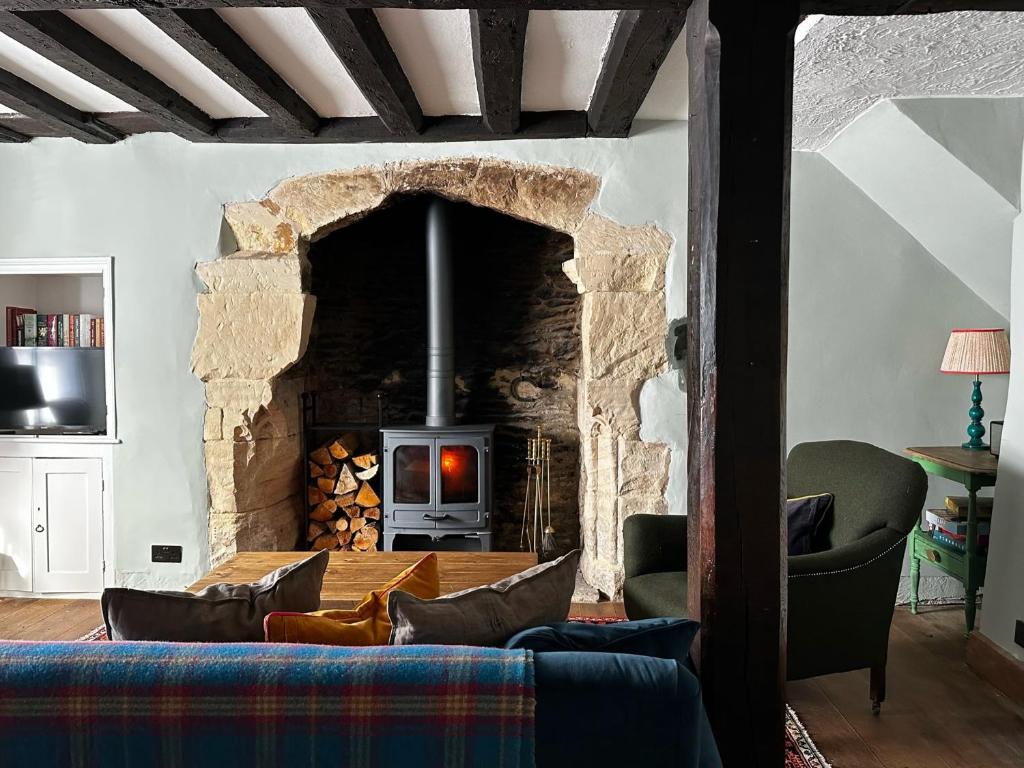 een woonkamer met een stenen open haard en een bank bij Cosy Cottage in Lechlade in Lechlade