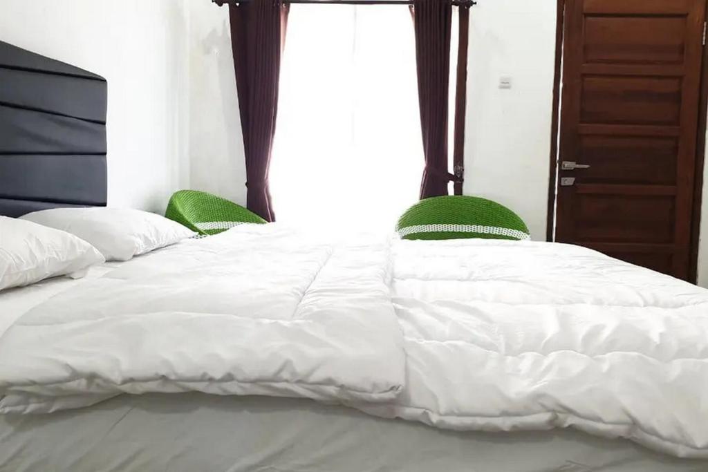 ein Bett mit zwei grünen Stühlen neben einem Fenster in der Unterkunft Anugrah Bromo Homestay at Desa Wisata Bromo Mitra RedDoorz in Tosari