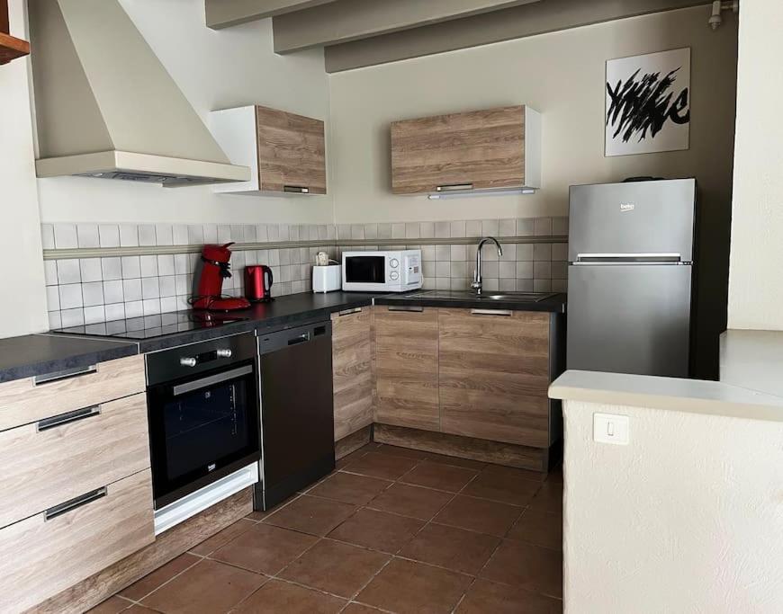 a kitchen with black appliances and wooden cabinets at Maison cosy avec parking gratuit in Jarnac