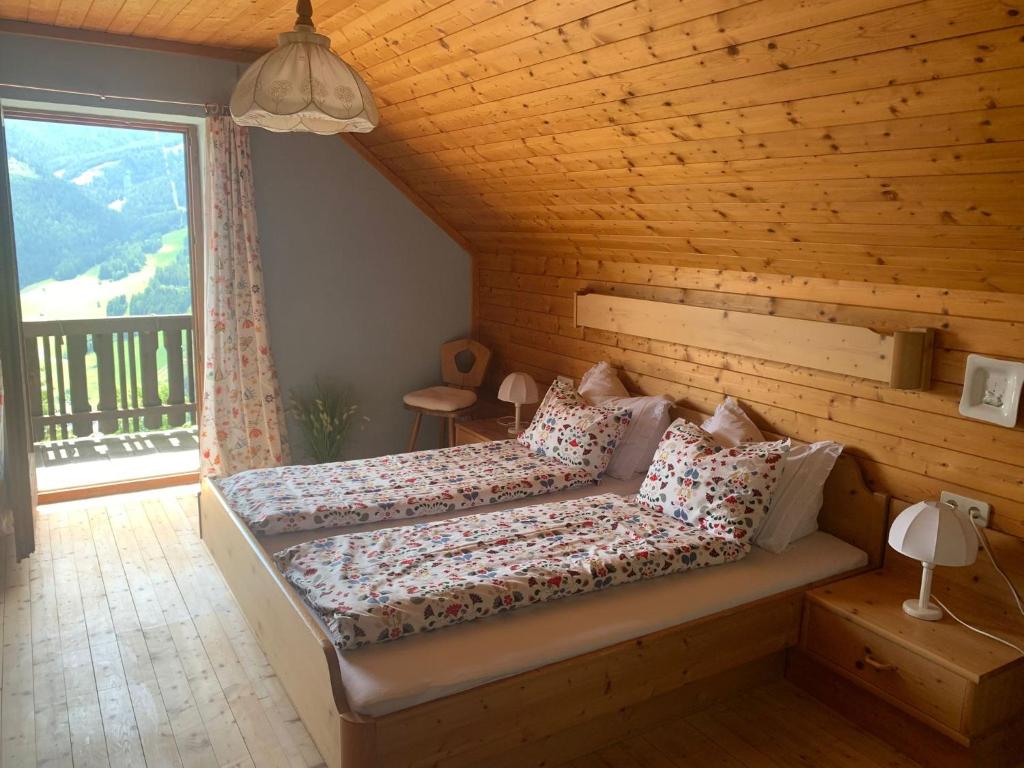 a bedroom with a bed and a large window at Sonnenplatz Appartment Ploninger LANDHAUS in Bad Kleinkirchheim