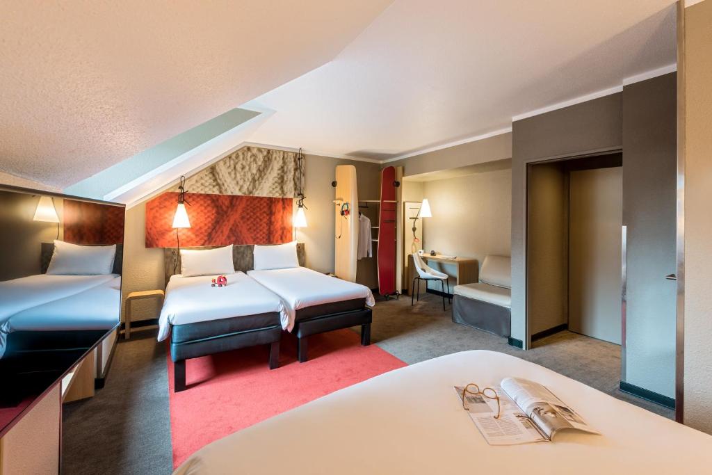 ibis Hotel Regensburg City في ريغنسبورغ: غرفة فندقية بسريرين ومكتب