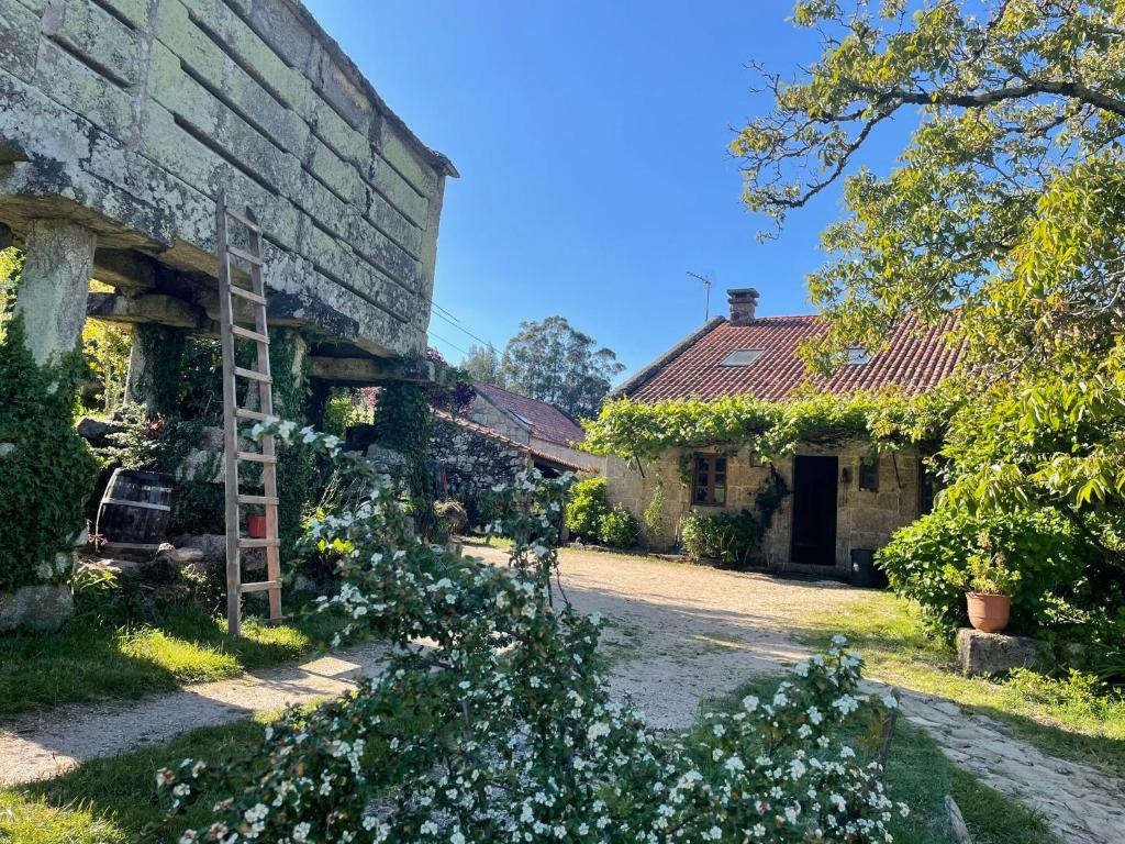 an old stone building with a yard with flowers at Casa Rural O Bergando in Cotobade