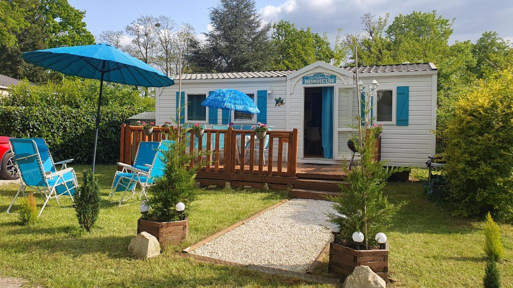 ein winziges Haus mit zwei Stühlen und einem Regenschirm in der Unterkunft La Maison du bonheur Mobil-home camping 3 étoiles Paris à 45 Km in Saint-Chéron