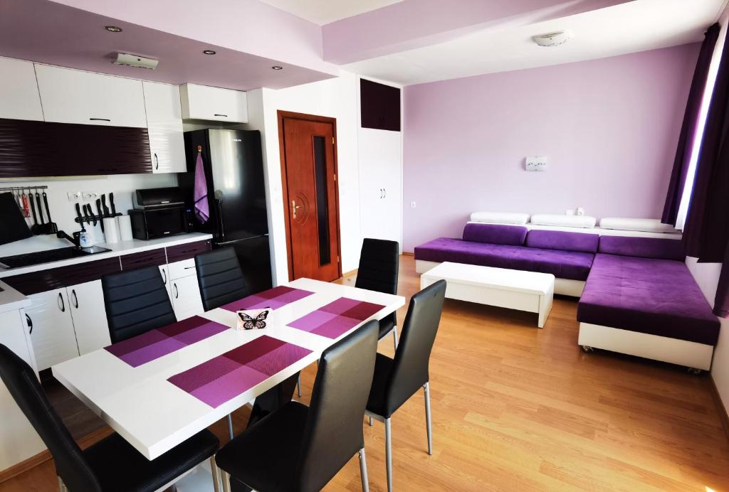 eine Küche und ein Wohnzimmer mit einem Tisch und lila Stühlen in der Unterkunft Апартамент 204 Студенец in Pamporowo