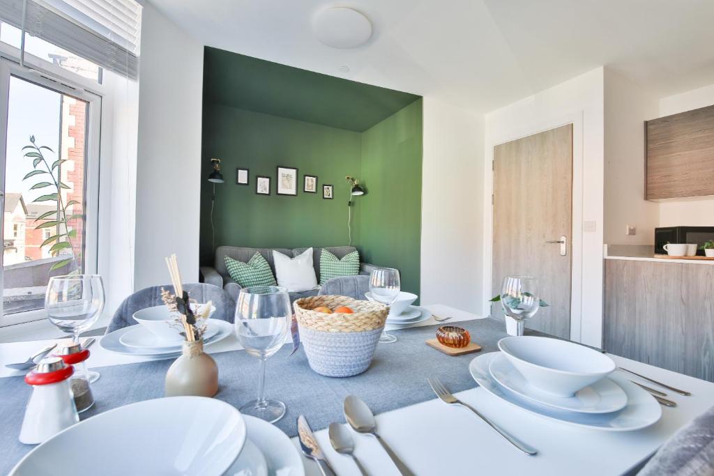 1 bedroom apartment near Cardiff Town Centre في كارديف: غرفة طعام مع طاولة مع الأطباق وكؤوس النبيذ