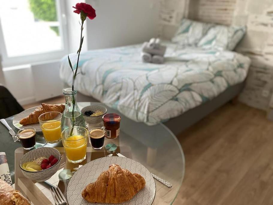 une table en verre avec des aliments et des boissons pour le petit-déjeuner sur un lit dans l'établissement La Douce Angevine - La Perruche - Proche centre, à Angers