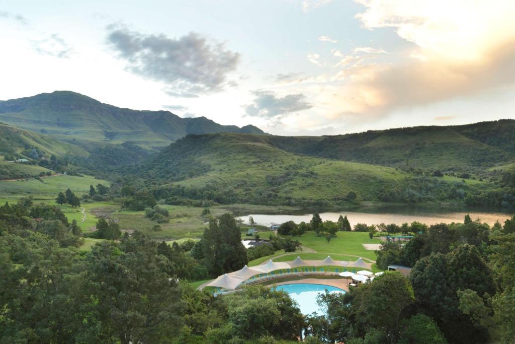 an aerial view of a golf course with a lake and mountains at Drakensberg Sun Resort in Winterton