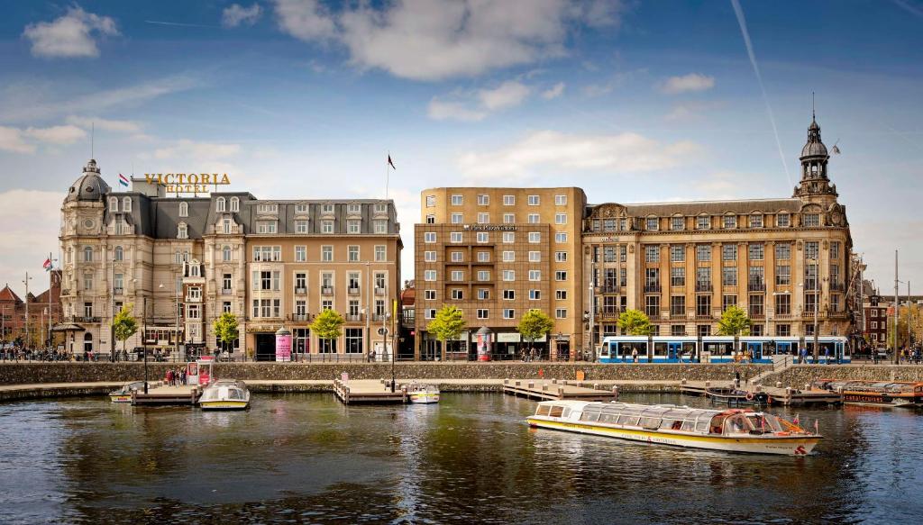 een stad met boten in het water voor gebouwen bij Park Plaza Victoria Amsterdam in Amsterdam