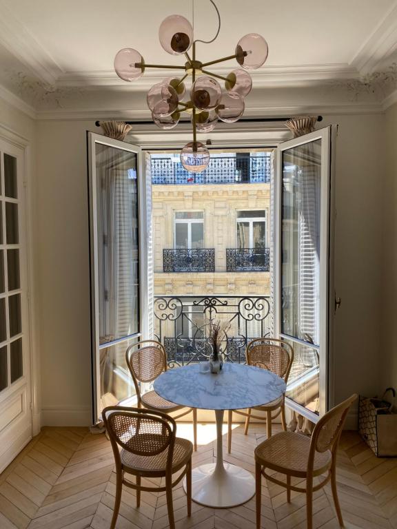 a dining room with a table and chairs and a window at Paris 8 golden triangle - fancy brand new appt in historic building in Paris