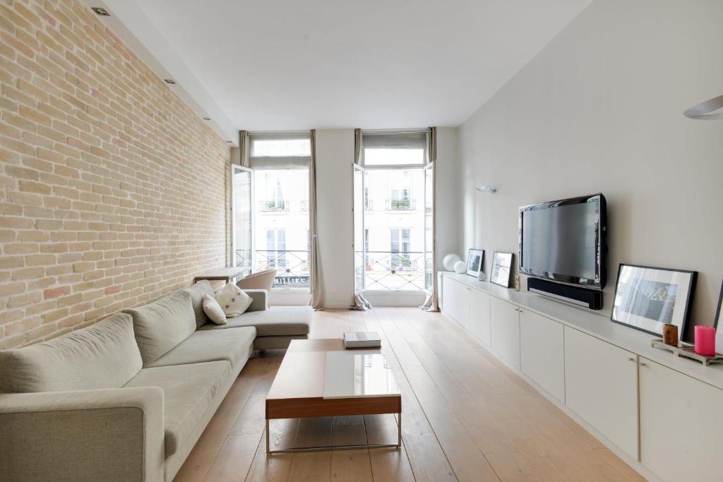 a living room with a couch and a brick wall at Appartement Neuf Saint-Honoré - Tuileries in Paris