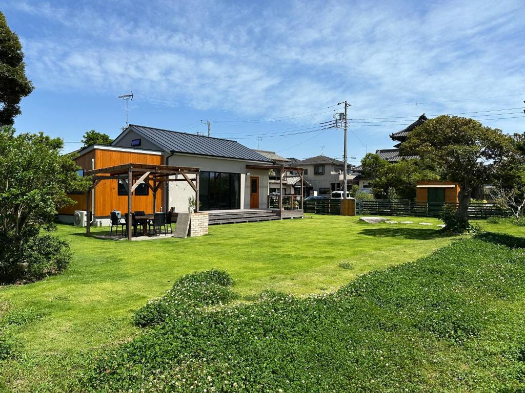 ein Haus mit einem Hof mit einem Rasenplatz in der Unterkunft ワンちゃんと泊まれるコテージ　西野納屋 in Kujukuri