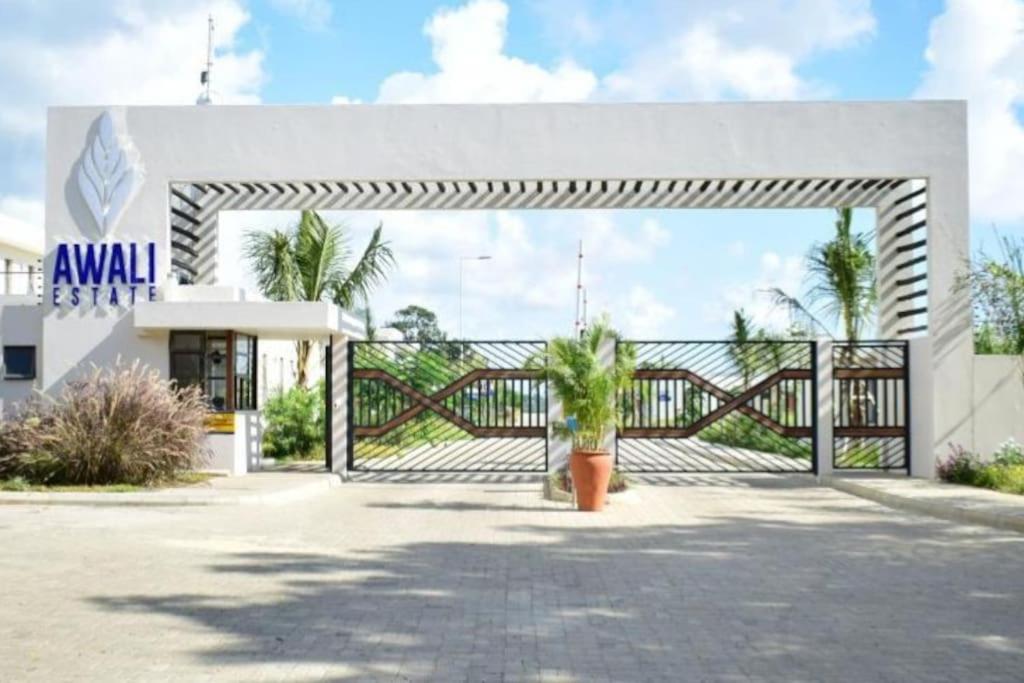 a white building with a gate and palm trees at Awali Villa B9 in Kilifi