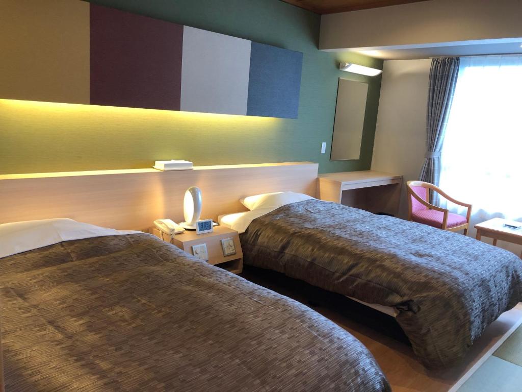 a hotel room with two beds and a window at Kirishima Hotel in Kirishima