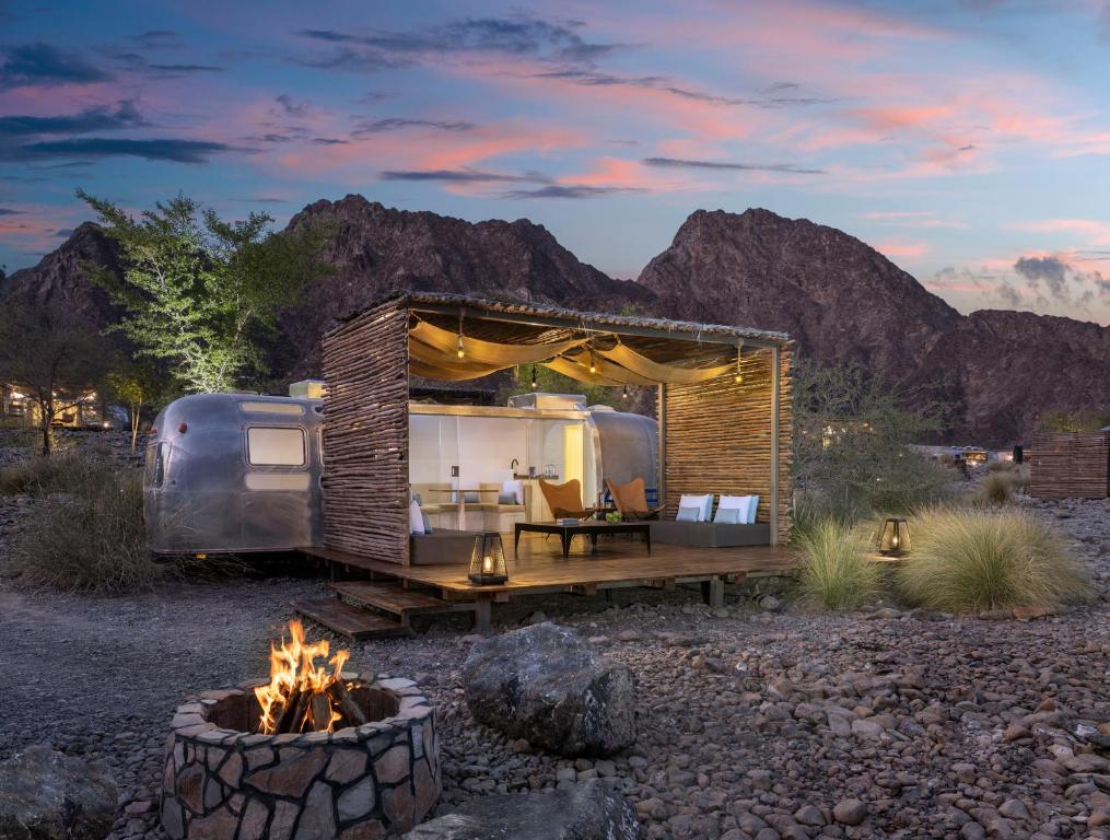 an exterior view of a tiny house with a fire pit at Hatta Sedr Trailers Resort in Hatta