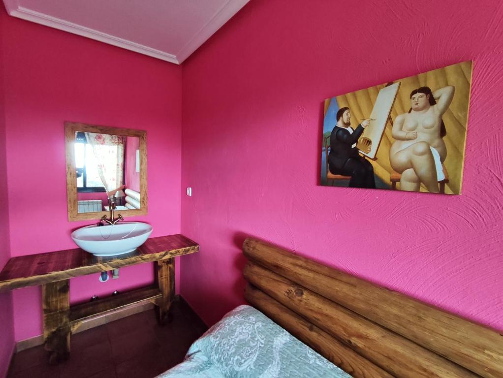 - une chambre avec des murs roses, un lavabo et un lit dans l'établissement La Pérgola, à La Cabrera