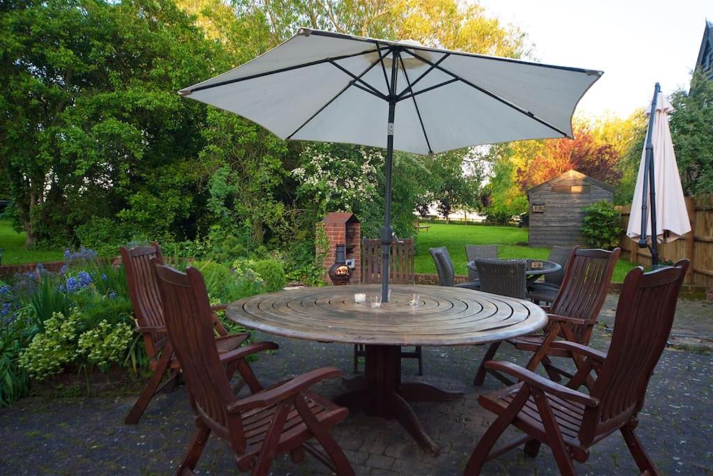 een terrastafel met een parasol en stoelen bij Stunning barn conversion ideal for large families in Bildeston