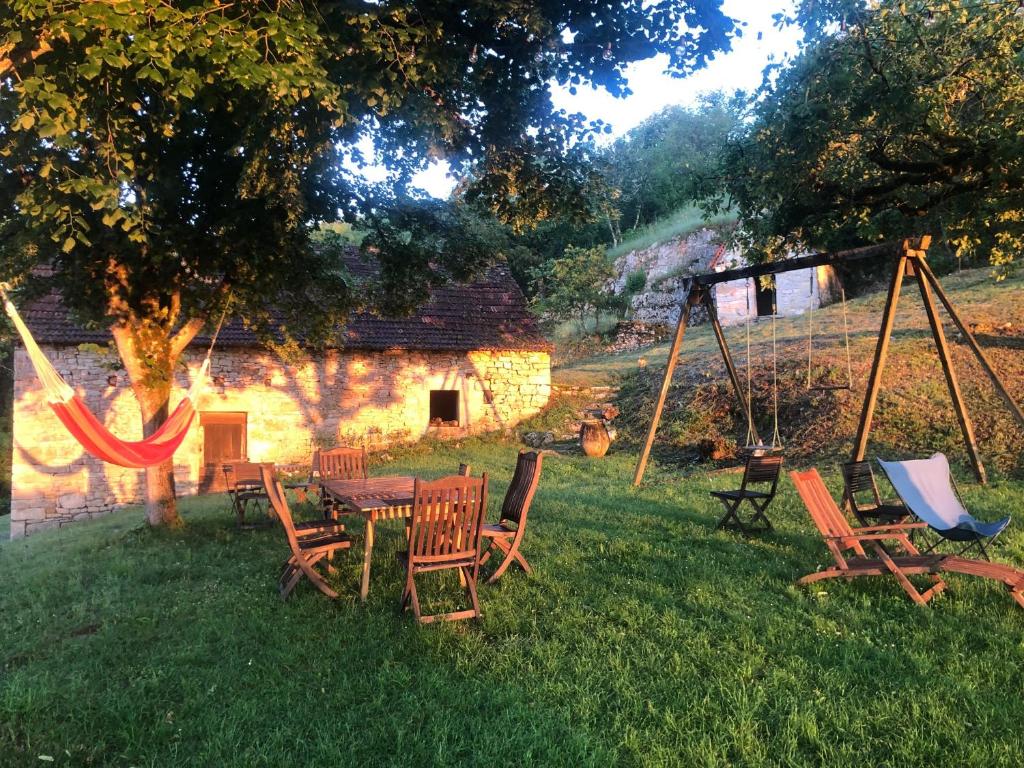 einen Garten mit Stühlen, einem Tisch und Schaukeln in der Unterkunft Art en Célé-chambres d'hôtes in Corn