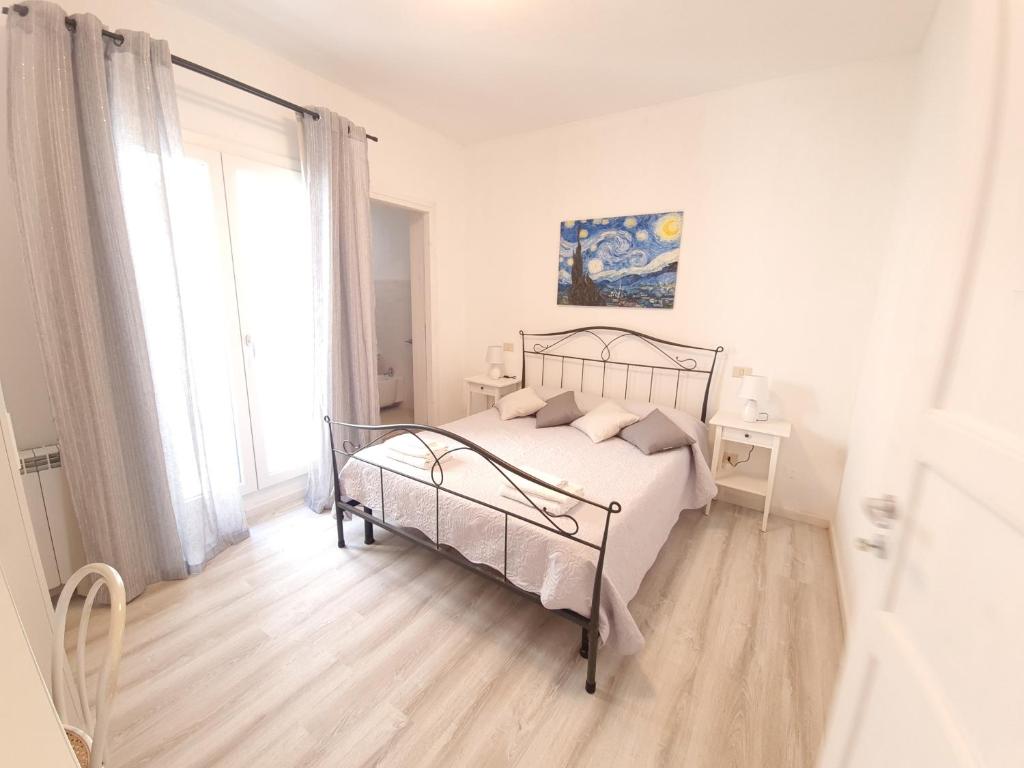 een witte slaapkamer met een bed en een raam bij Margherita Guest House in Olbia