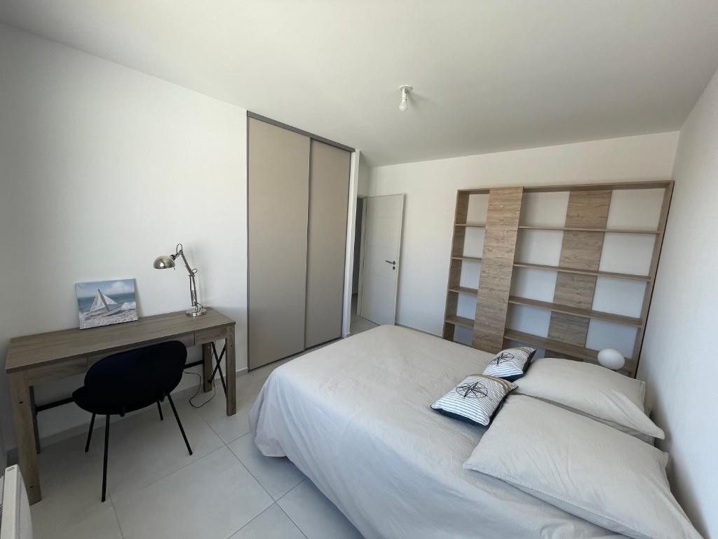 - une petite chambre avec un lit et un bureau dans l'établissement L’Oliveraie, à Narbonne