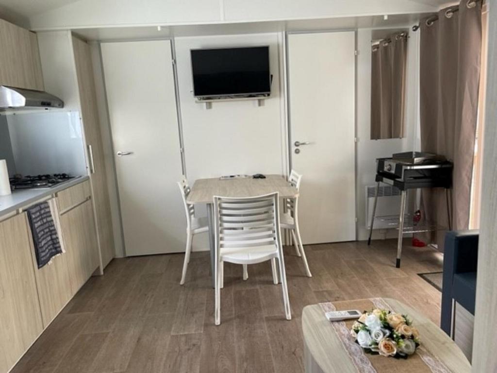 a small kitchen with a table and chairs in a room at Mobil-home (Clim, Tv)- Camping Narbonne-Plage 4* - 022 in Narbonne-Plage