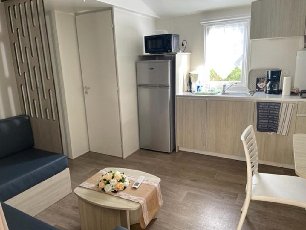 a small living room with a table and a kitchen at Mobil-home (Clim, Tv)- Camping Narbonne-Plage 4* - 022 in Narbonne-Plage