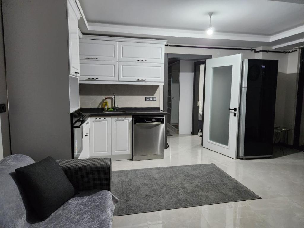 La cuisine est équipée de placards blancs et d'un réfrigérateur noir. dans l'établissement Sahil dairesi, à Atakum