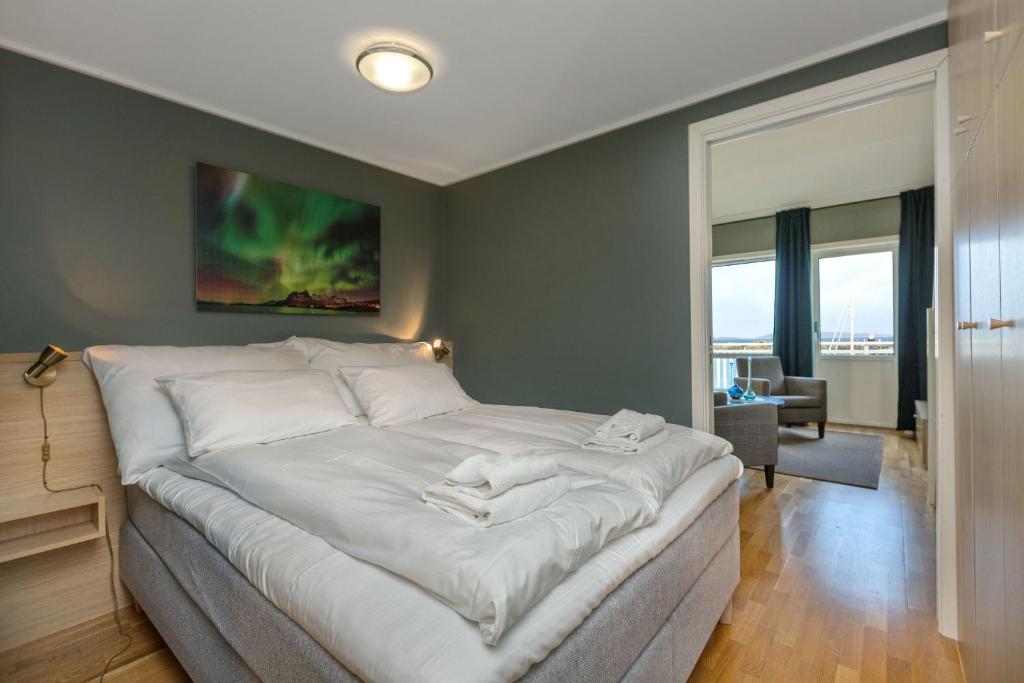 Kjerringøy Bryggehotell في بودو: غرفة نوم بسرير كبير مع شراشف بيضاء